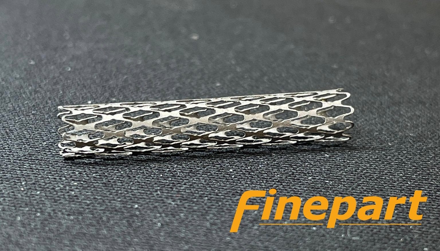Precision-cut medical stent manufactured using Finepart micro abrasive waterjet technology showing intricate lattice pattern and burr-free edges.