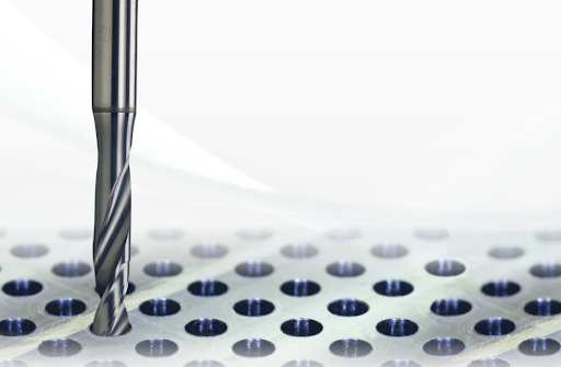 Close-up of a high-performance carbide drill positioned above a precision-drilled metal surface, illustrating the role of ultra-fine carbide grades in achieving consistent accuracy and durability in demanding micro-machining applications.